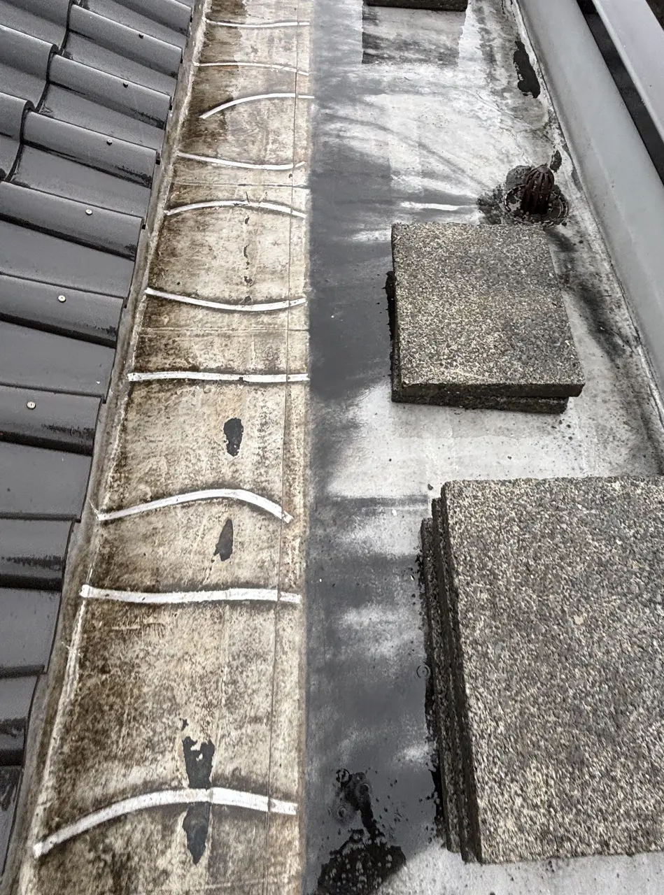 八王子市内の賃貸マンション屋上 防水面の上で積み重ねて寄せたコンクリートブロック板